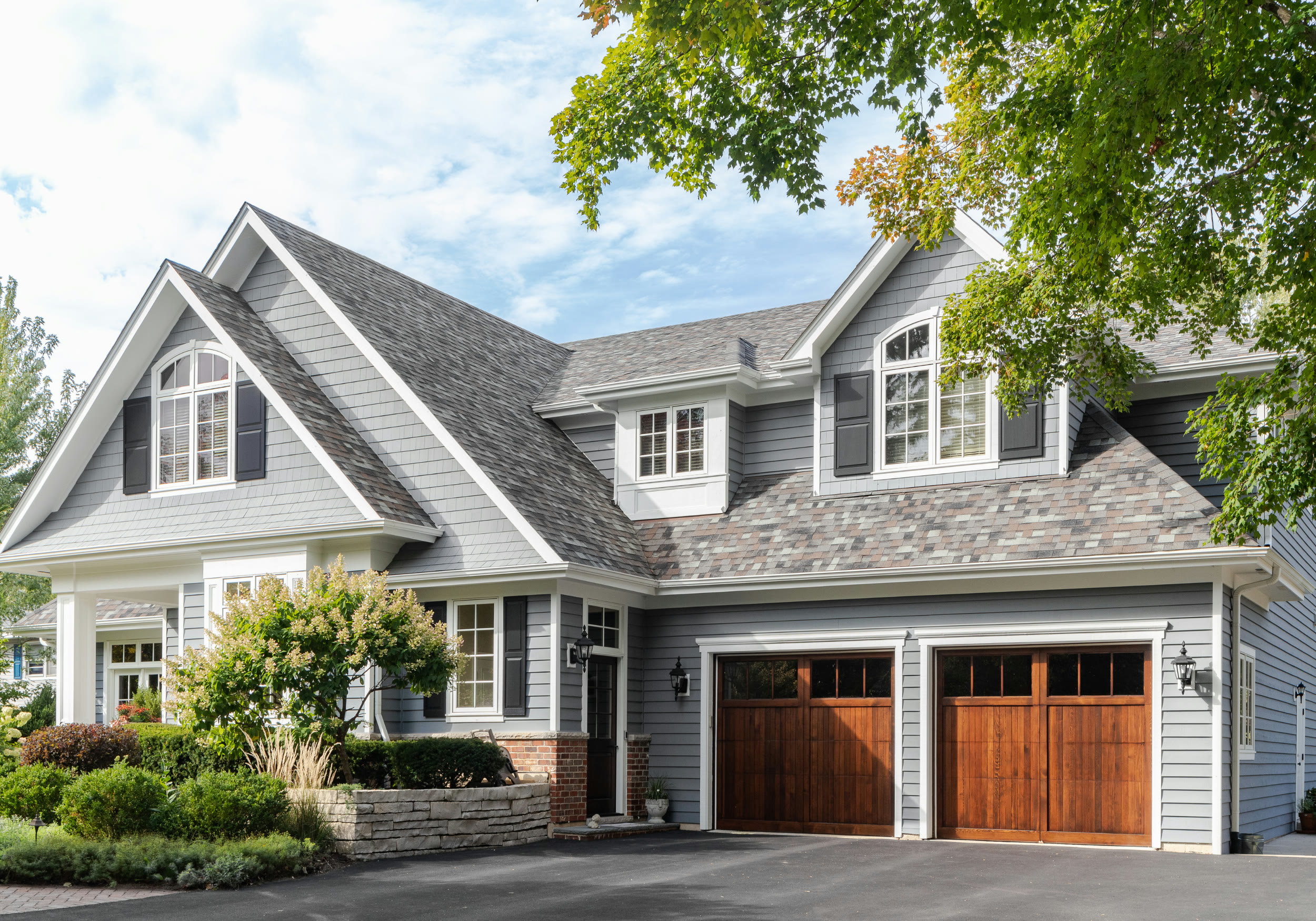 A gray two-story home with a two-car garage and wooden doors